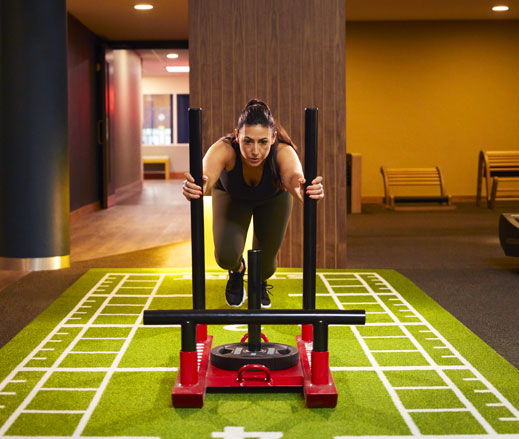 Image of a woman in the gym pushing a weighted sled