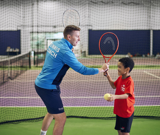 Image of a coach leading a kids tennis lesson at David Lloyd Clubs