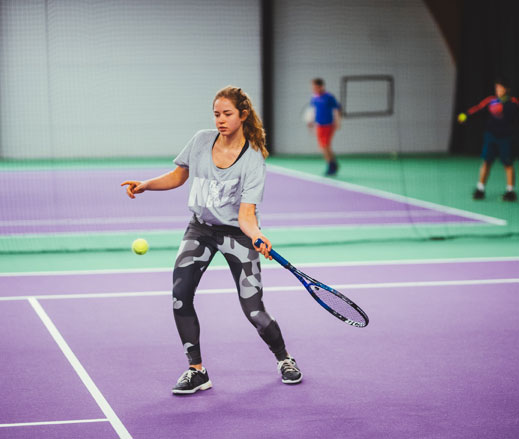 Image of teenage girl hitting a forehand on an indoor tennis court at David Lloyd